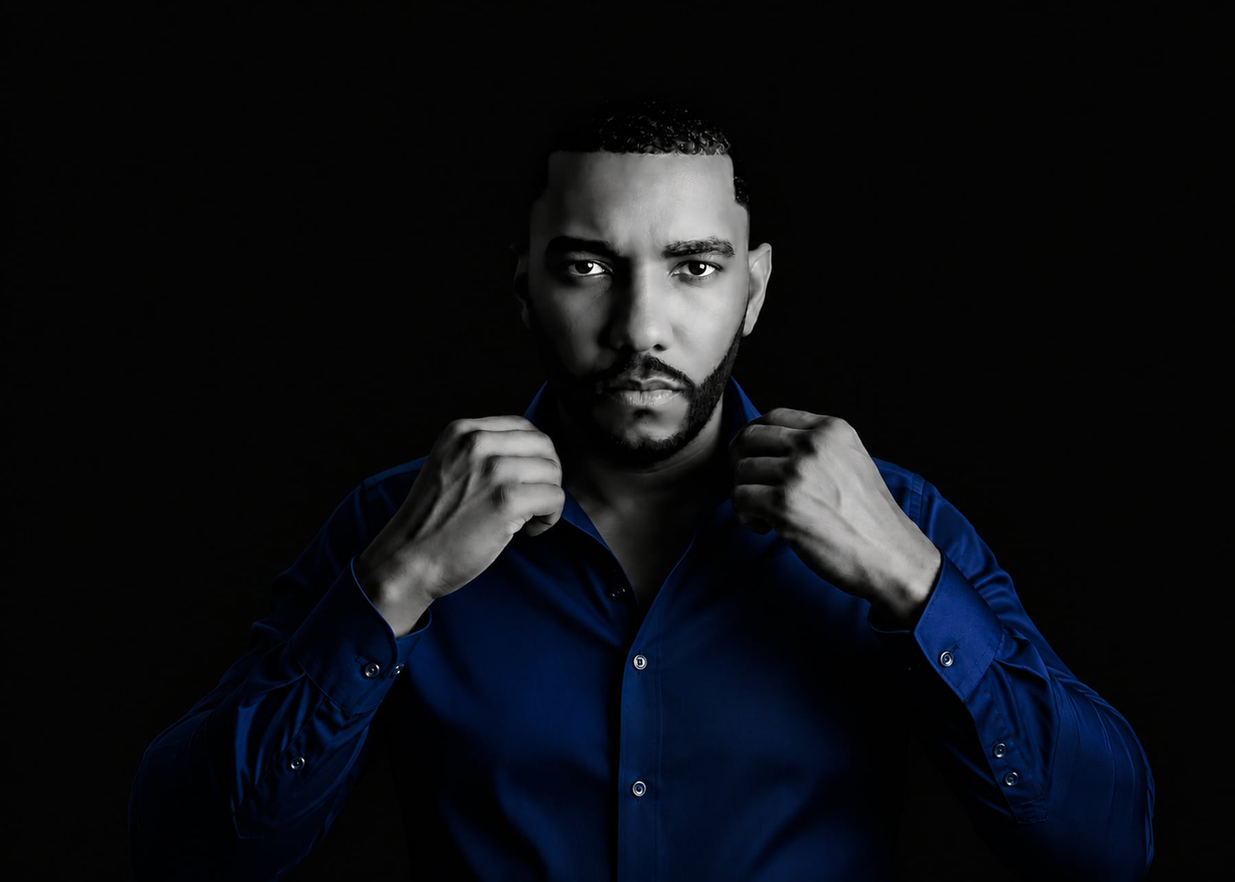 Michael Harte Jr. in a blue shirt against a dark background